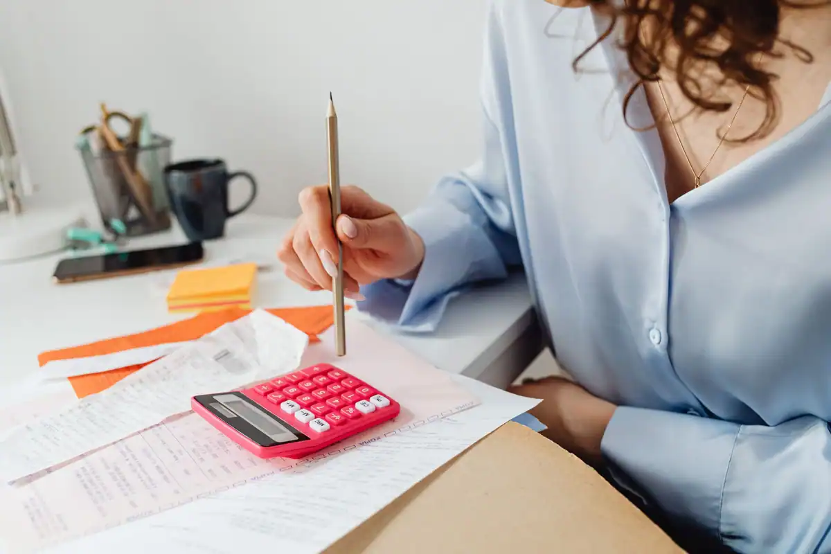 Femeie care calculează cheltuielile cu un calculator și documente pe birou