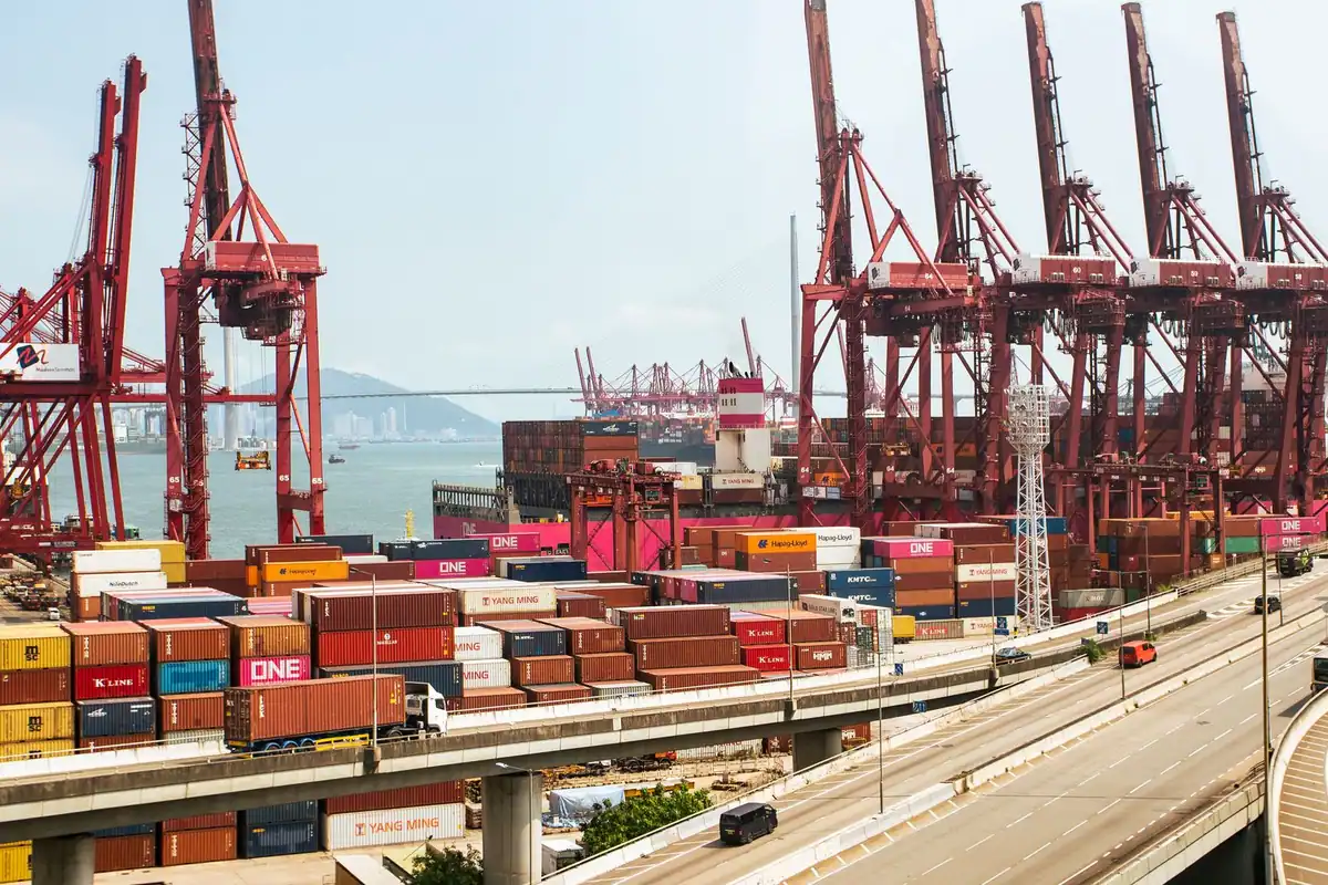 Port comercial aglomerat cu macarale roșii și containere stivuite