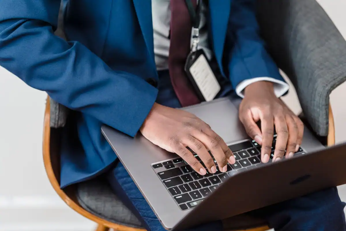 Bărbat în costum albastru, la laptop, într-un birou, scriind un mesaj către client