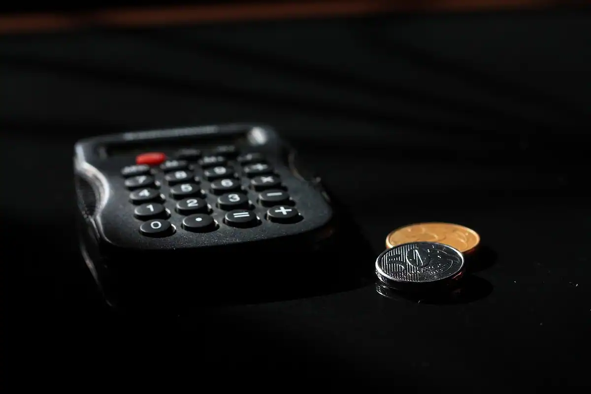 Calculator și monede pe un birou, pentru calculul cheltuielilor firmei