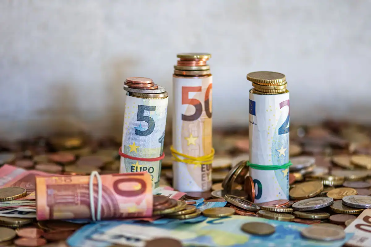 Bancnote rulate și monede pe o masă, simbol al rezervei de numerar