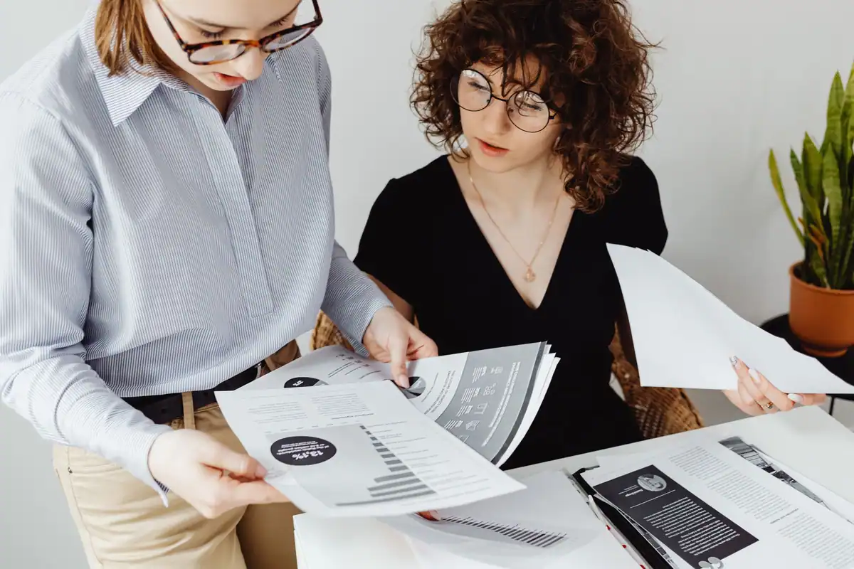 Două femei care analizează împreună documente financiare în birou