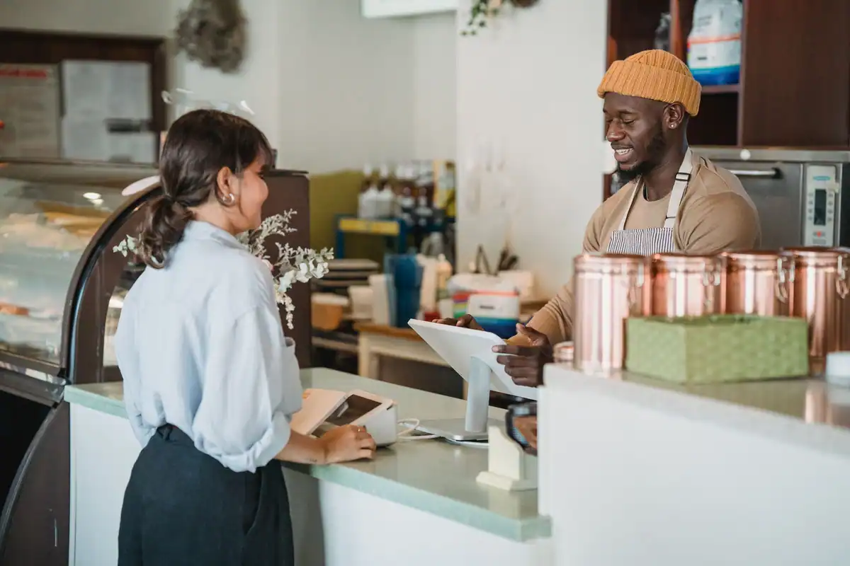 Barista și client într-o discuție prietenoasă la tejgheaua unei cafenele